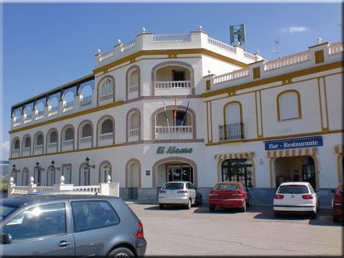 Hotel El Remo con coches aparcados en el exterior, día soleado.