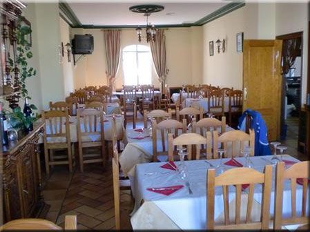 Comedor de restaurante con mesas dispuestas para el servicio, sillas y ventanal con cortinas.