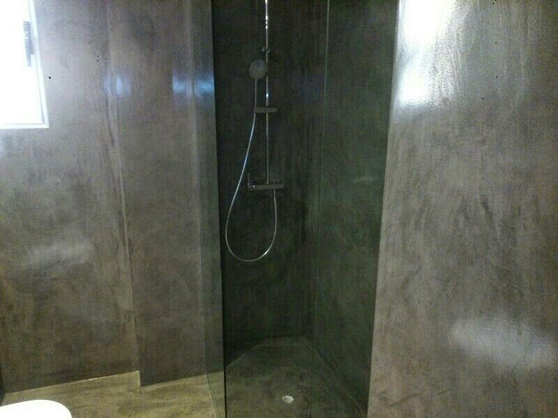 Ducha con azulejos grises, puerta de cristal y cabezal de ducha plateado.