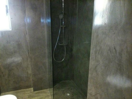 Ducha con azulejos grises, puerta de cristal y cabezal de ducha plateado.