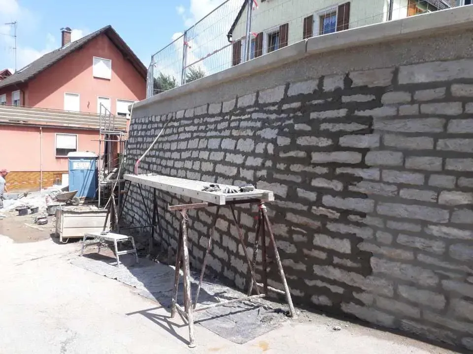 Bau-Eisen GmbH, Mauer mit Bauwerkzeug