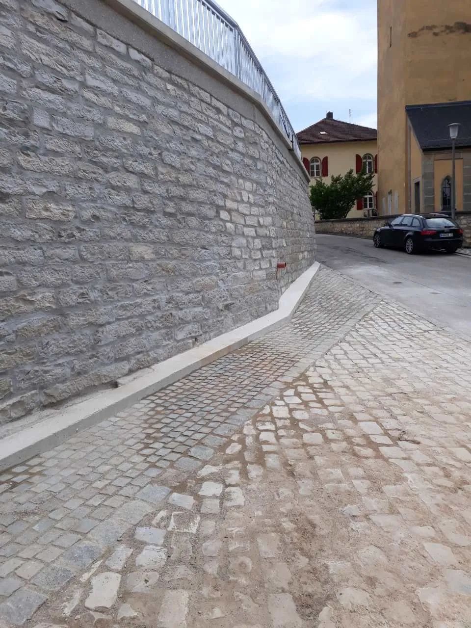 Bau-Eisen GmbH, gepflasterte Straße und Mauer