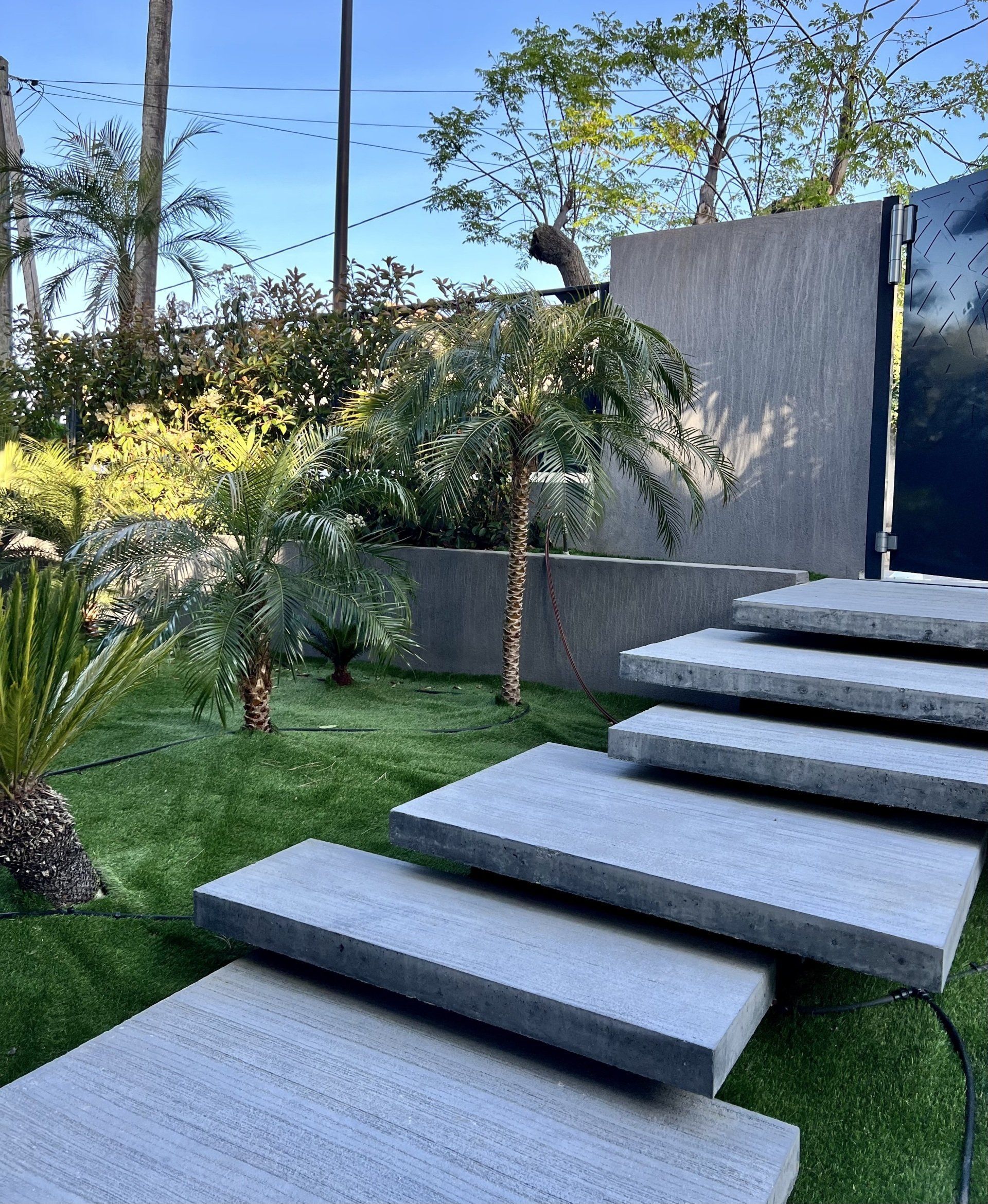 Escalier en béton et jardin paysager : accès à une résidence moderne entourée de verdure