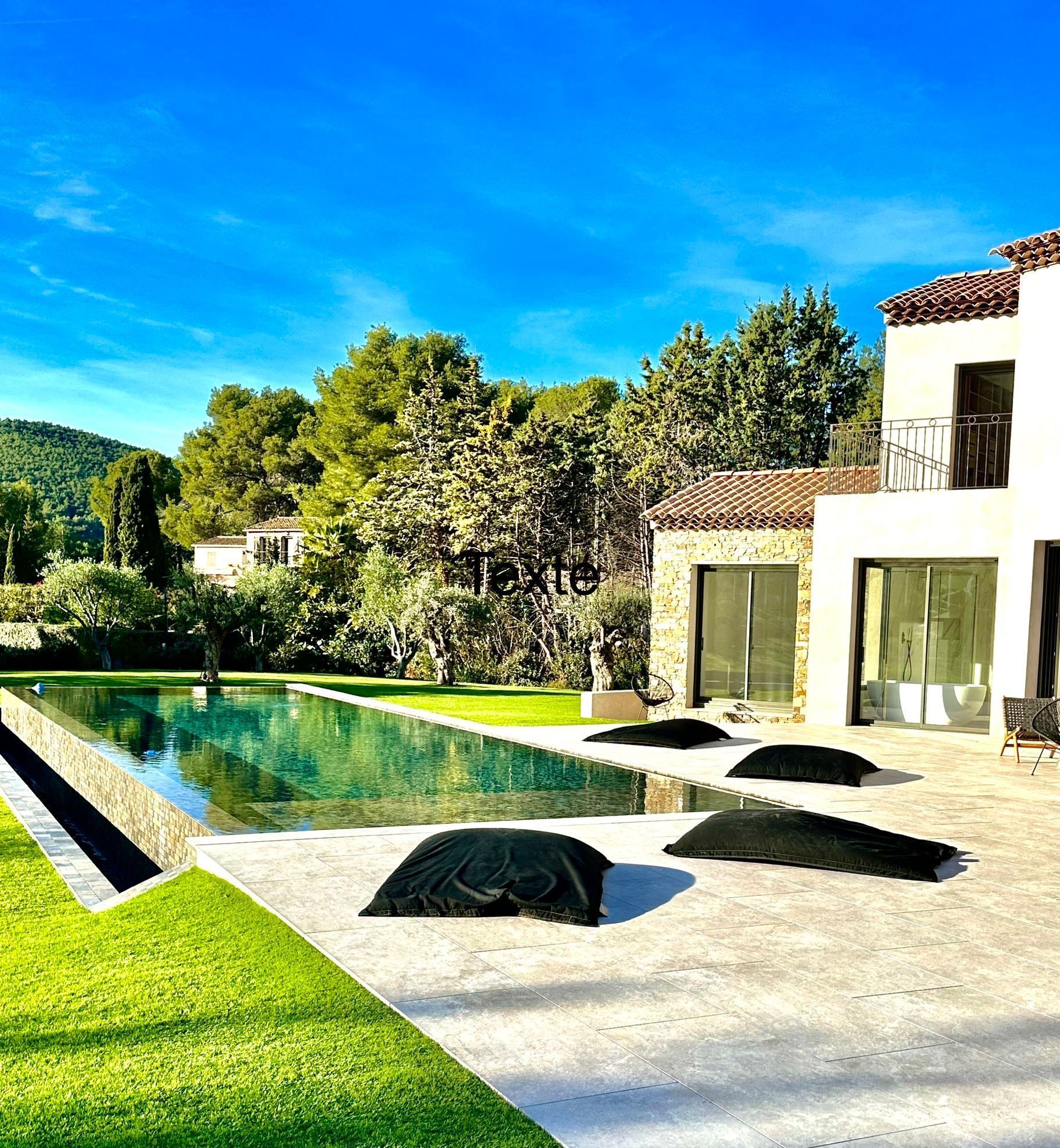 Maison et bassin entourés d’un jardin luxuriant et de grands arbres