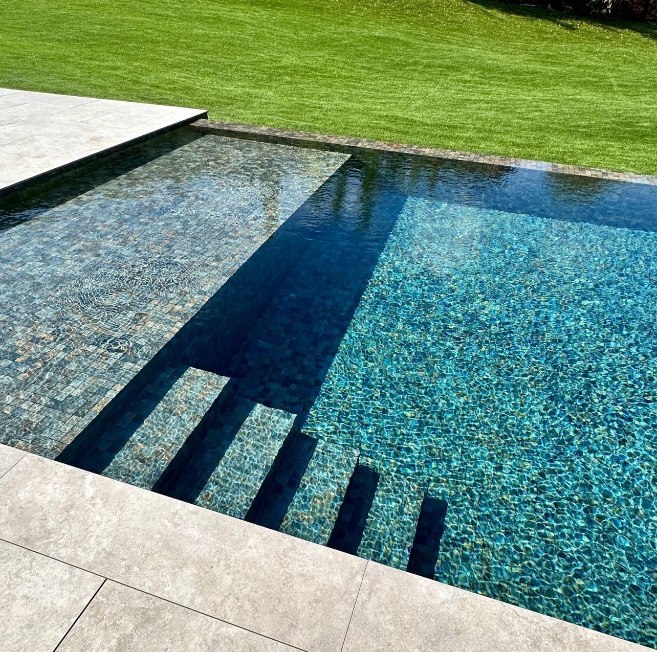 Piscine avec reflets scintillants et margelles en pierre