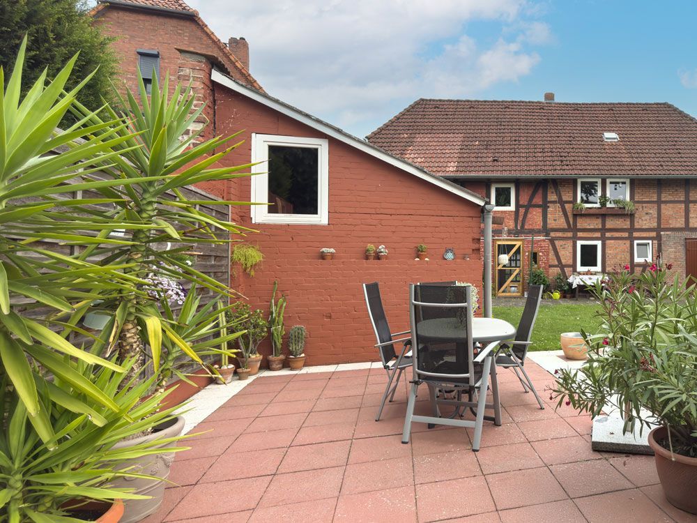 Ein Gebäude aus roten Backsteinen und eine Terrasse mit kleinem Tisch und Stühlen, die vor einem traditionellen Fachwerkhaus stehen.