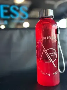 Una botella de agua roja con una correa está sobre una mesa.