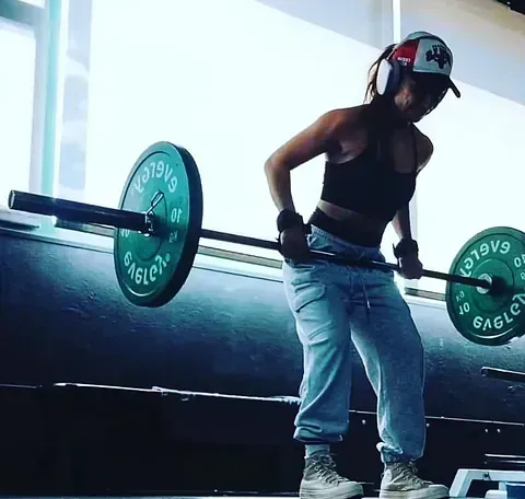Una mujer está levantando una barra en un gimnasio.