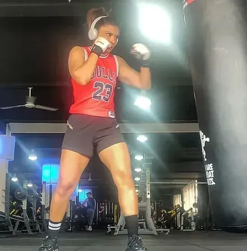 Una mujer con una camiseta de los Bulls está boxeando en un gimnasio.