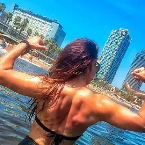 Una mujer en bikini flexiona sus músculos en el agua.
