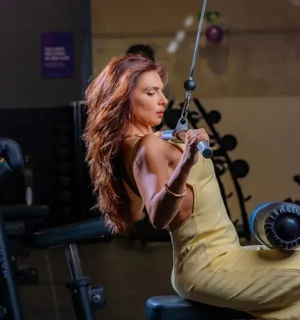 Una mujer con un vestido amarillo está haciendo ejercicios en una máquina en un gimnasio.