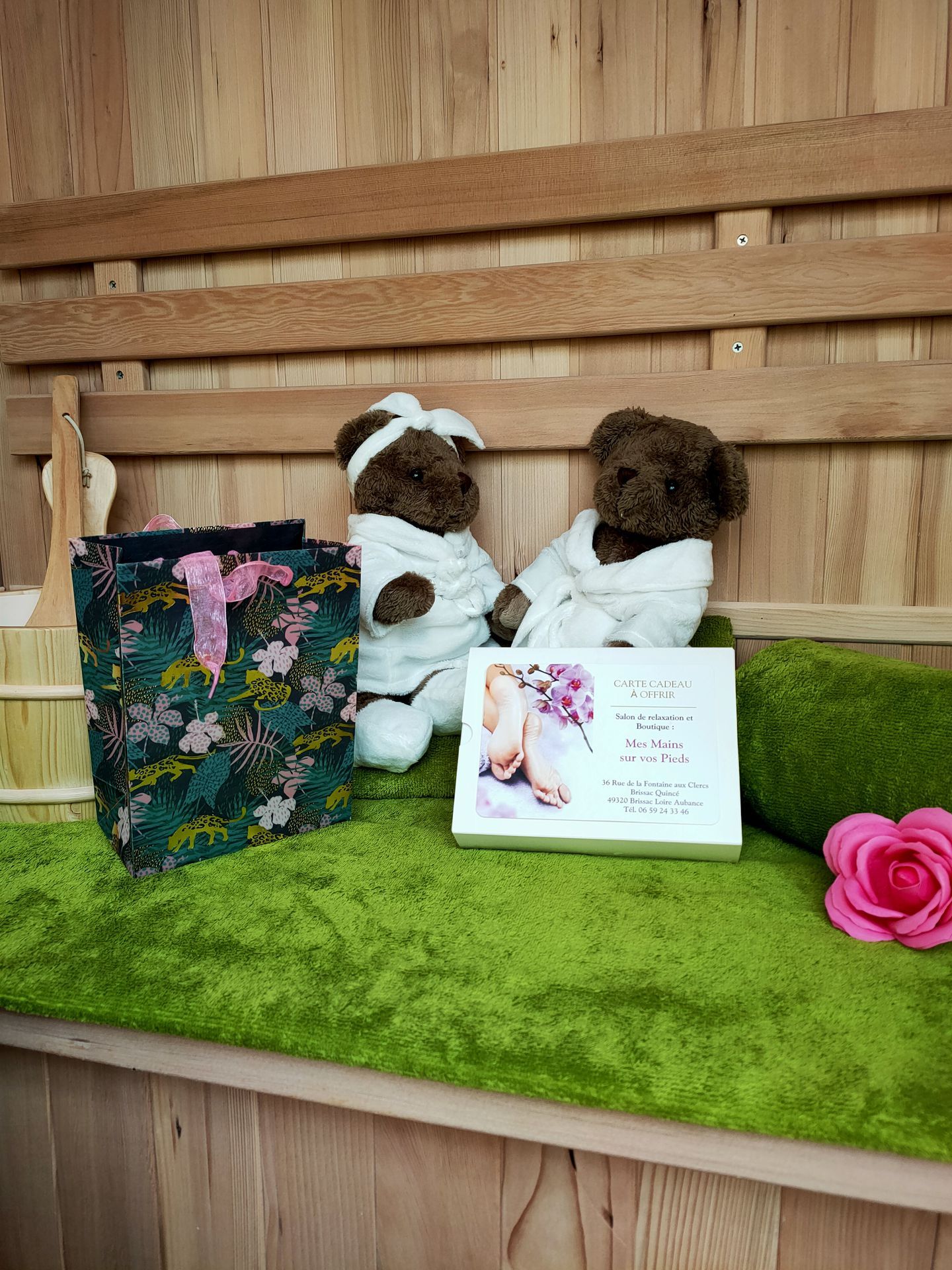 Deux oursons en peluche vêtus de peignoirs blancs posés à côté d'une carte-cadeau