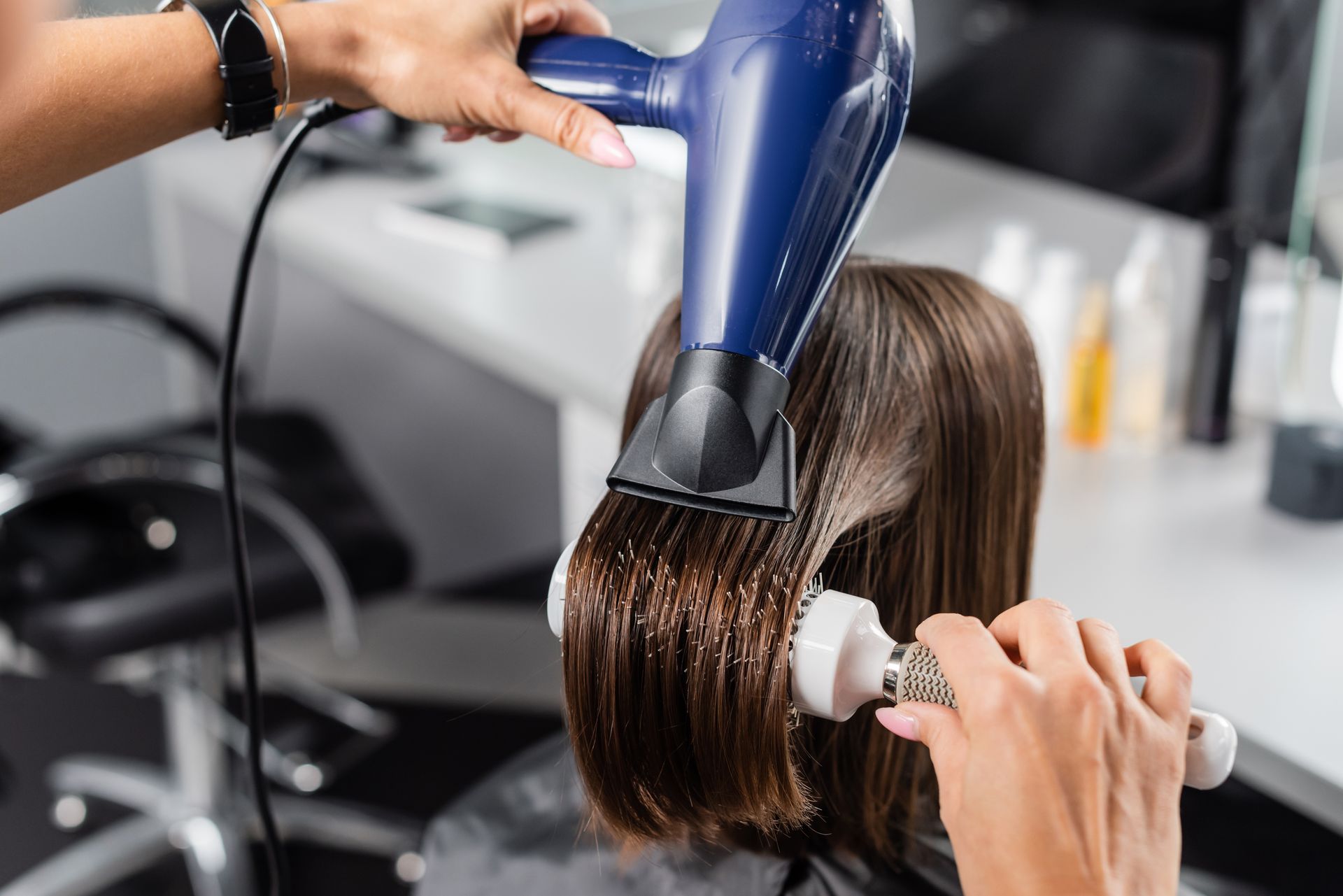 Une coiffeuse qui réalise un brushing sur cheveux court