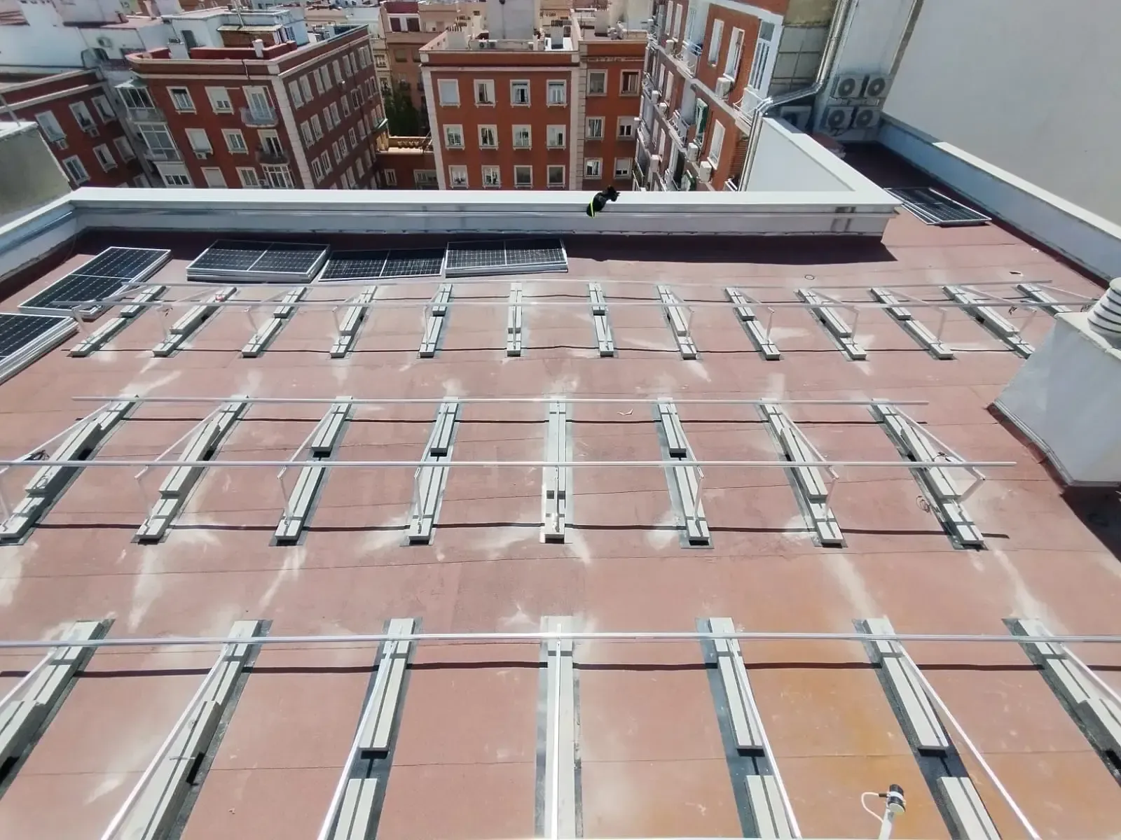 Azotea con hileras de paneles solares o tragaluces, con vistas a los edificios de ladrillo cercanos en una ciudad.