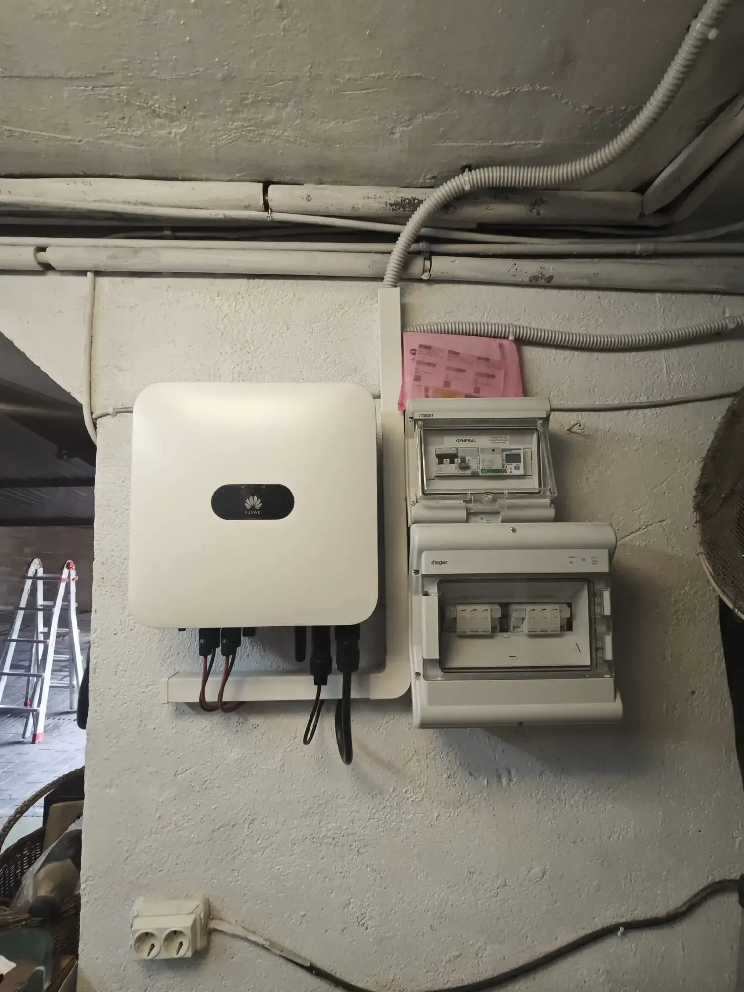 Panel eléctrico y contadores montados en la pared de un cuarto de servicio con cables y tuberías a la vista.