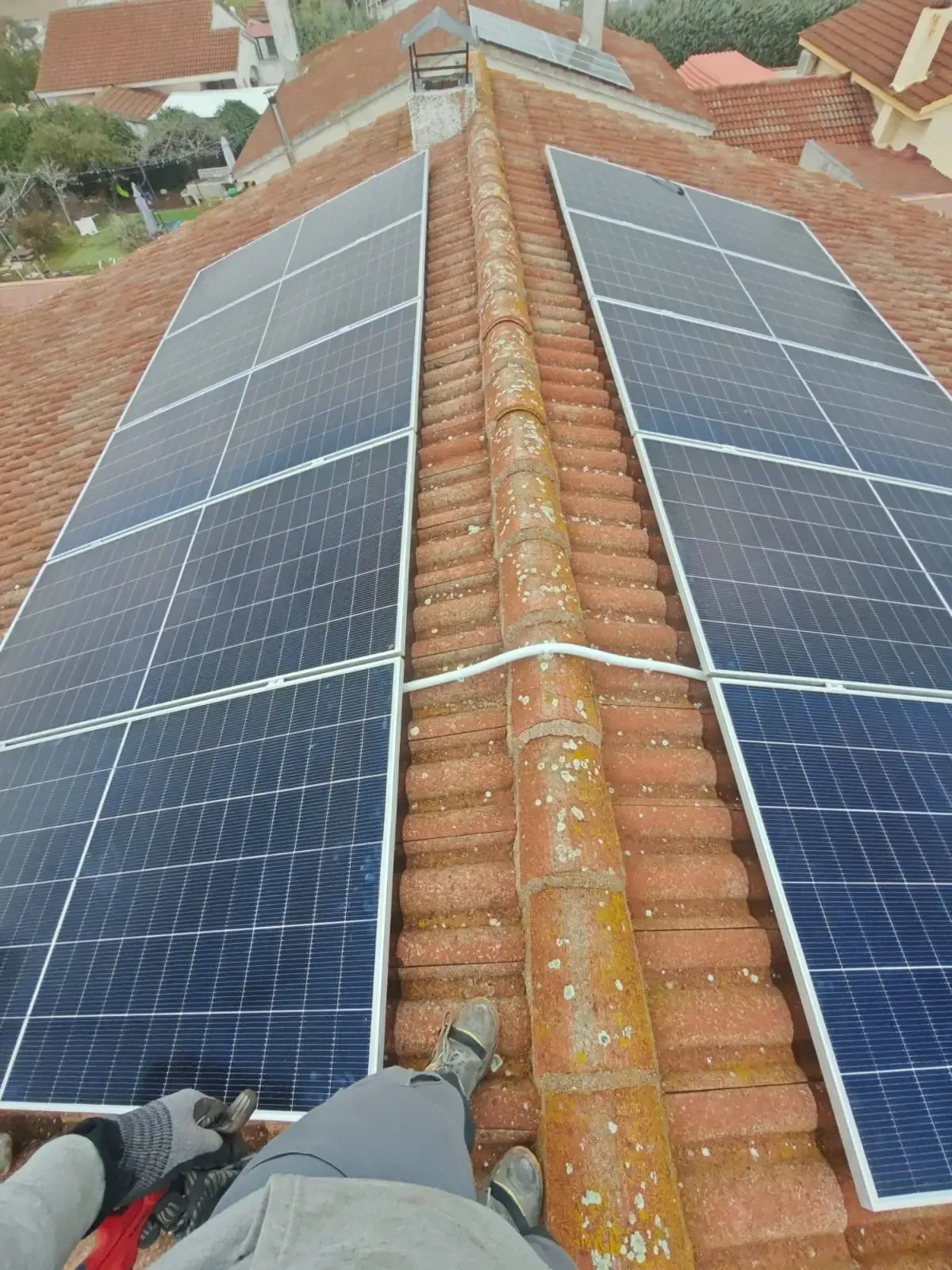 Tejado con paneles solares a ambos lados de la cumbrera, visto desde la perspectiva de un trabajador que se encuentra sobre el tejado.