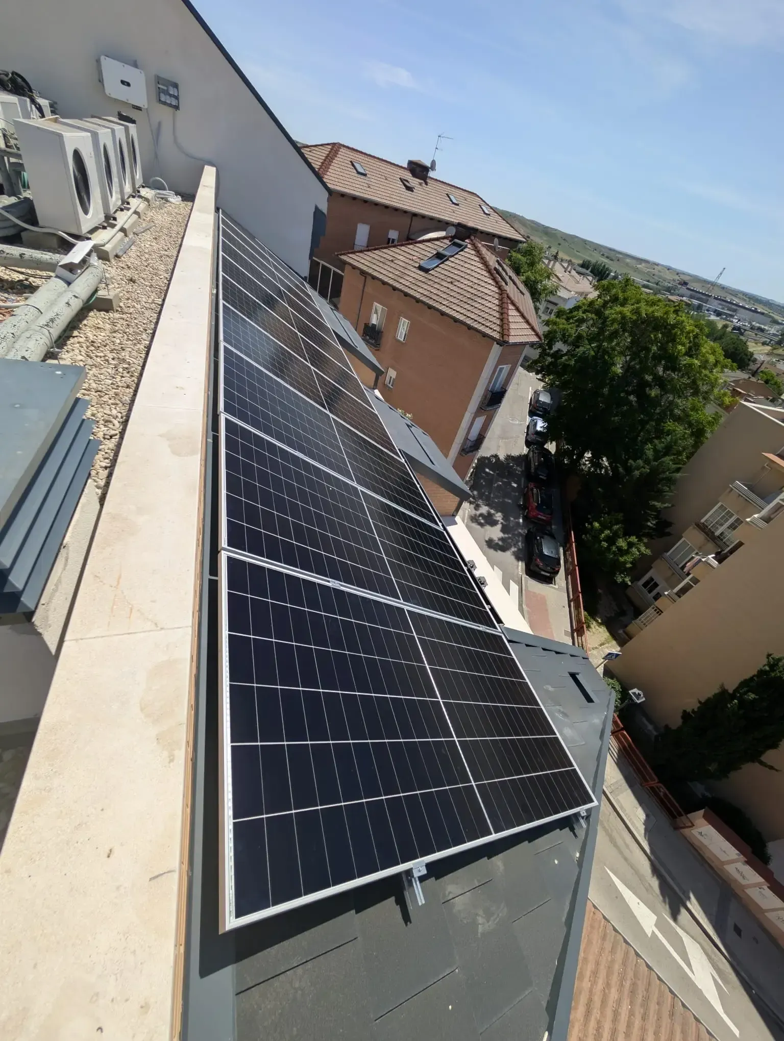 Paneles solares instalados en el tejado de una casa vecina en un día soleado.