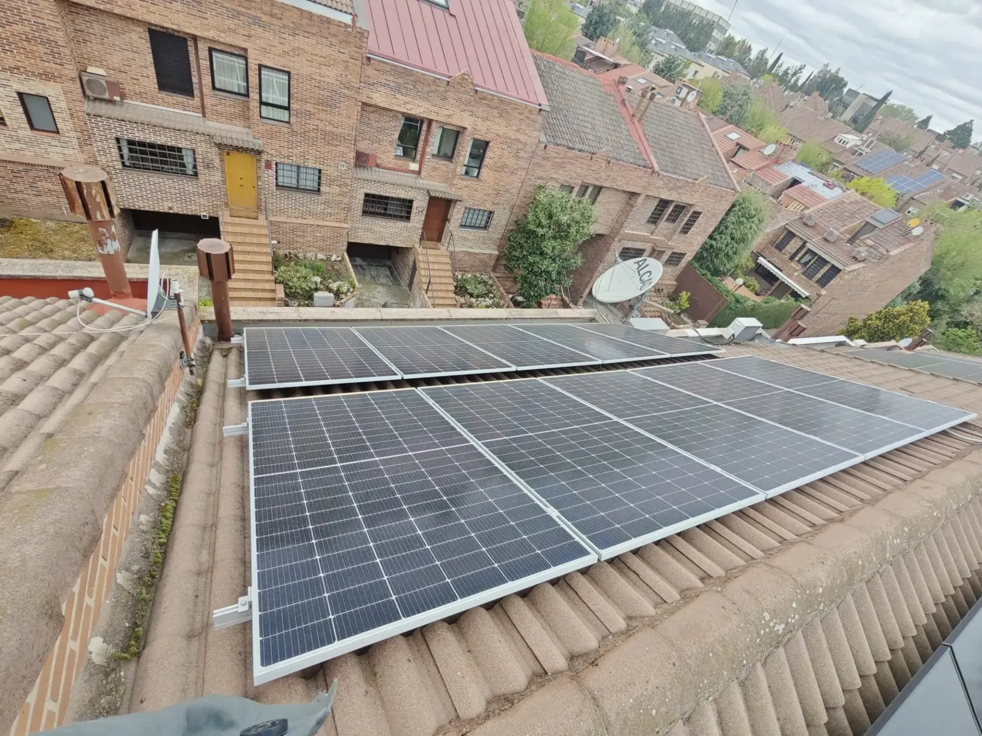 Paneles solares instalados en el tejado de una vivienda en un barrio residencial.