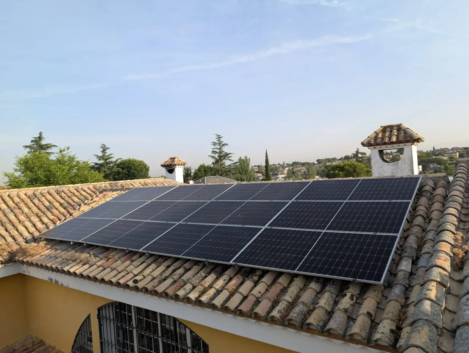 Paneles solares instalados en un tejado de tejas bajo un cielo despejado.
