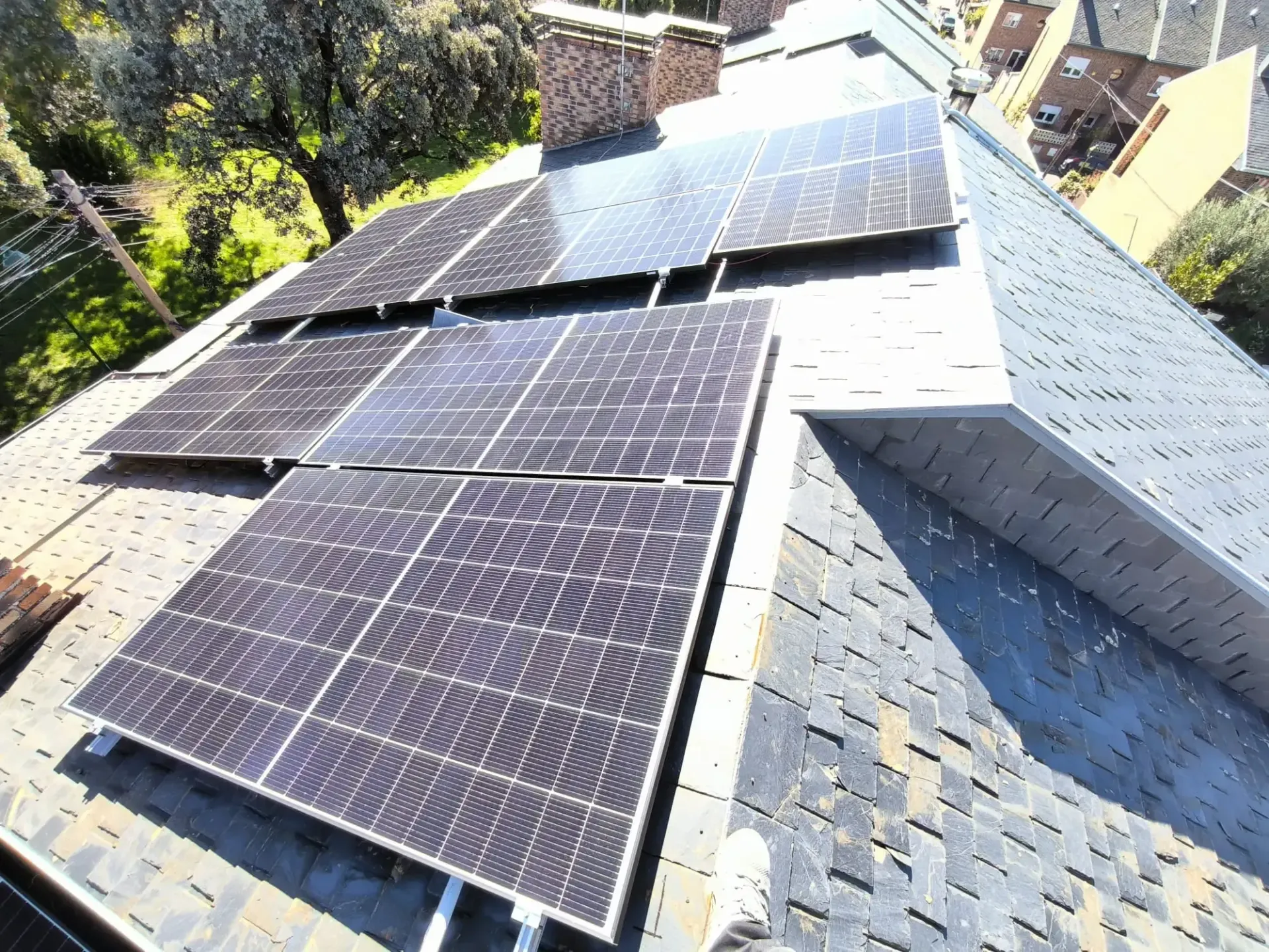 Paneles solares instalados en un tejado de tejas grises bajo la luz del sol.