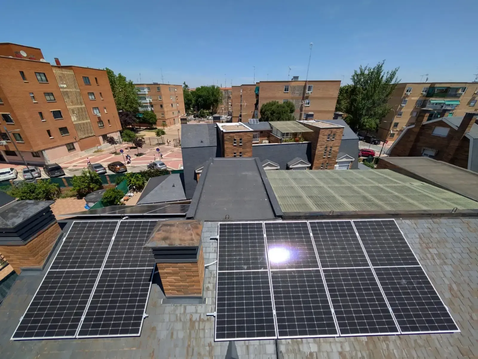 Azotea con paneles solares en edificios de apartamentos de ladrillo en un barrio urbano.