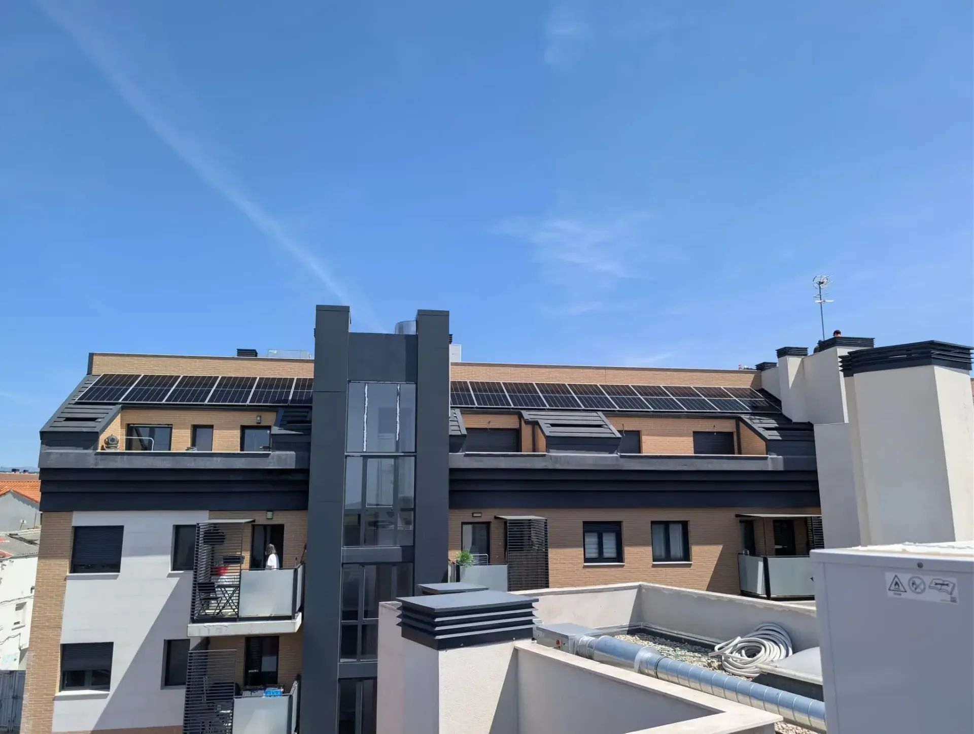 Edificios de apartamentos modernos con paneles solares bajo un cielo azul despejado.