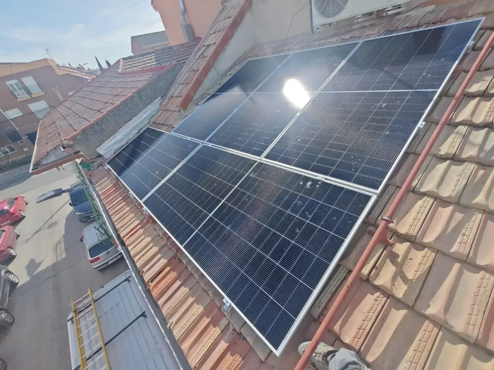 Paneles solares instalados en un tejado de tejas rojas bajo la luz del sol.