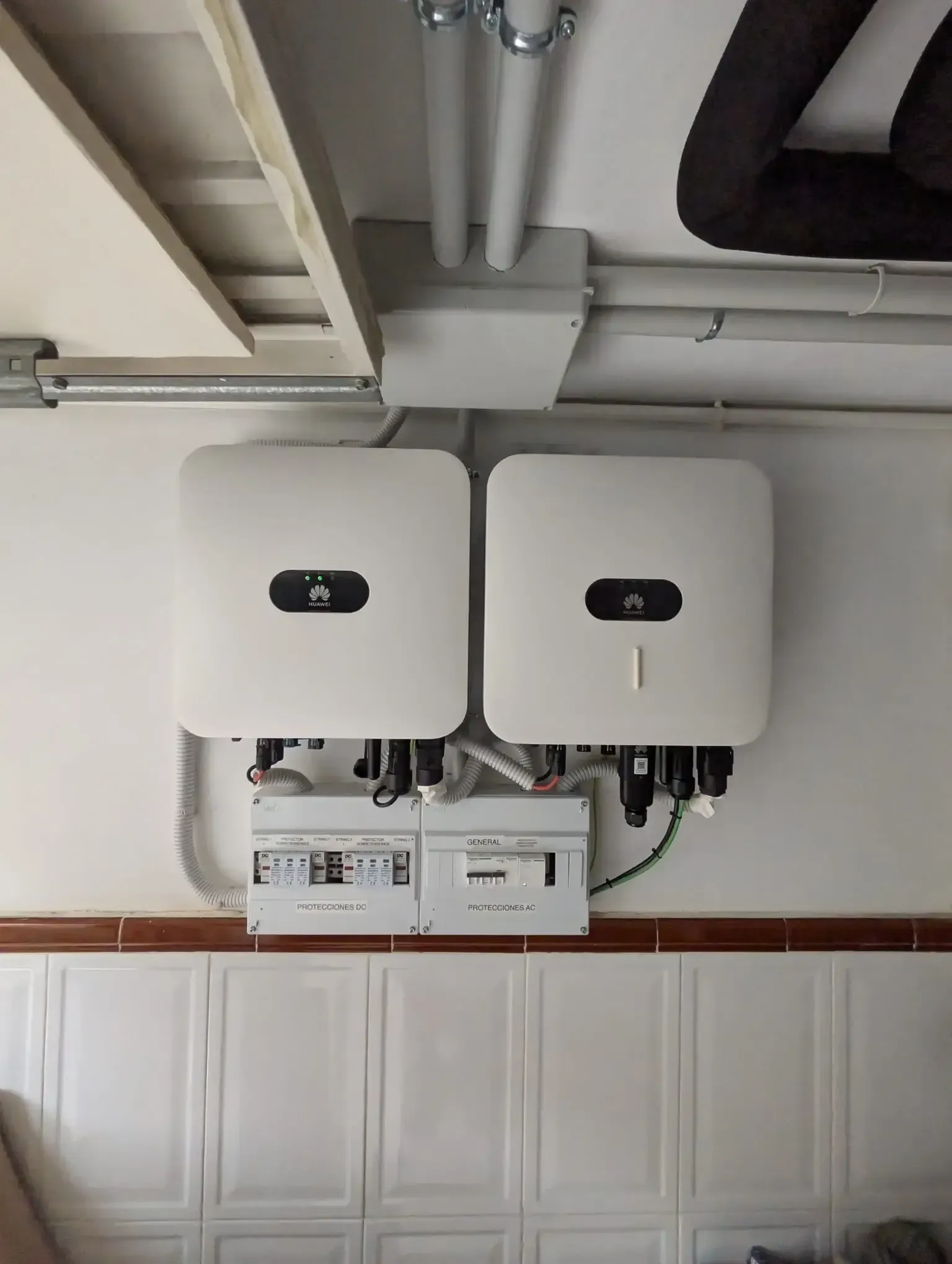 Dos unidades eléctricas blancas montadas en la pared, con tuberías y cableado, en un cuarto de servicio.