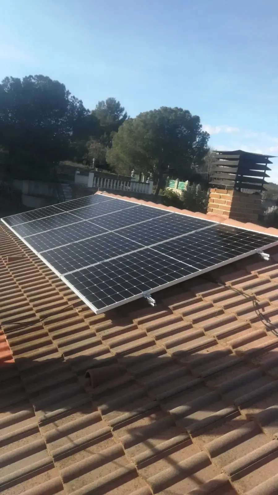 Paneles solares instalados en un tejado de tejas de terracota bajo un cielo azul despejado.