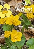 Nahaufnahme von rosa Magnolienblüten vor blauem Himmel mit dem Wort „Kleeblatt“ darüber.