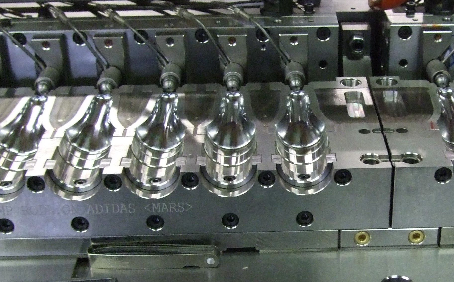 Moule métallique avec des rangées de pièces argentées brillantes sur une chaîne de montage de machines industrielles