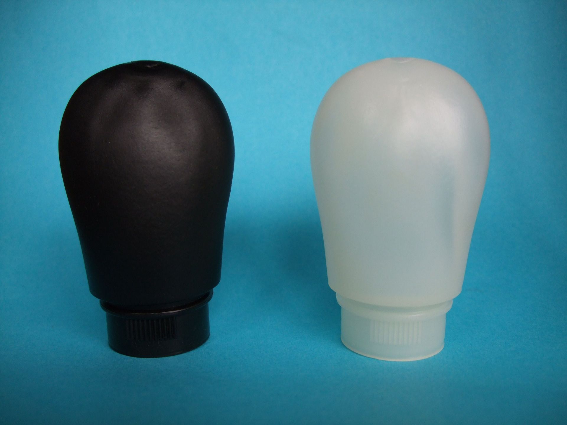Deux objets en forme d'ampoule, l'un noir et l'autre blanc, côte à côte sur un fond bleu.