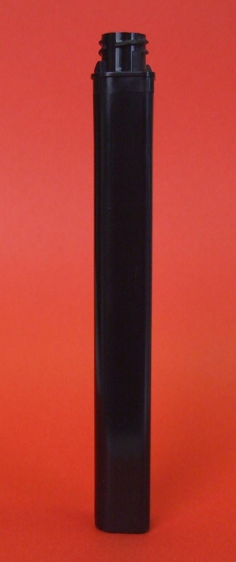 Bouteille ou tube cylindrique noir debout sur fond rouge