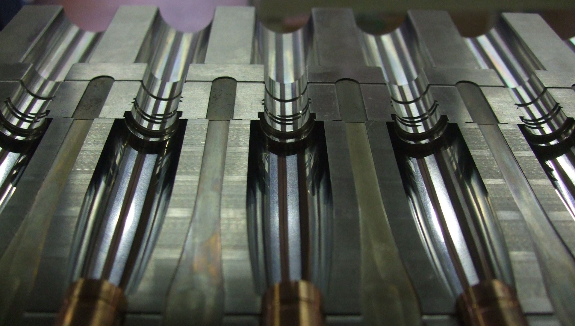 Gros plan sur une machine d'usine en métal brillant, équipée de plusieurs rouleaux ou lames parallèles.