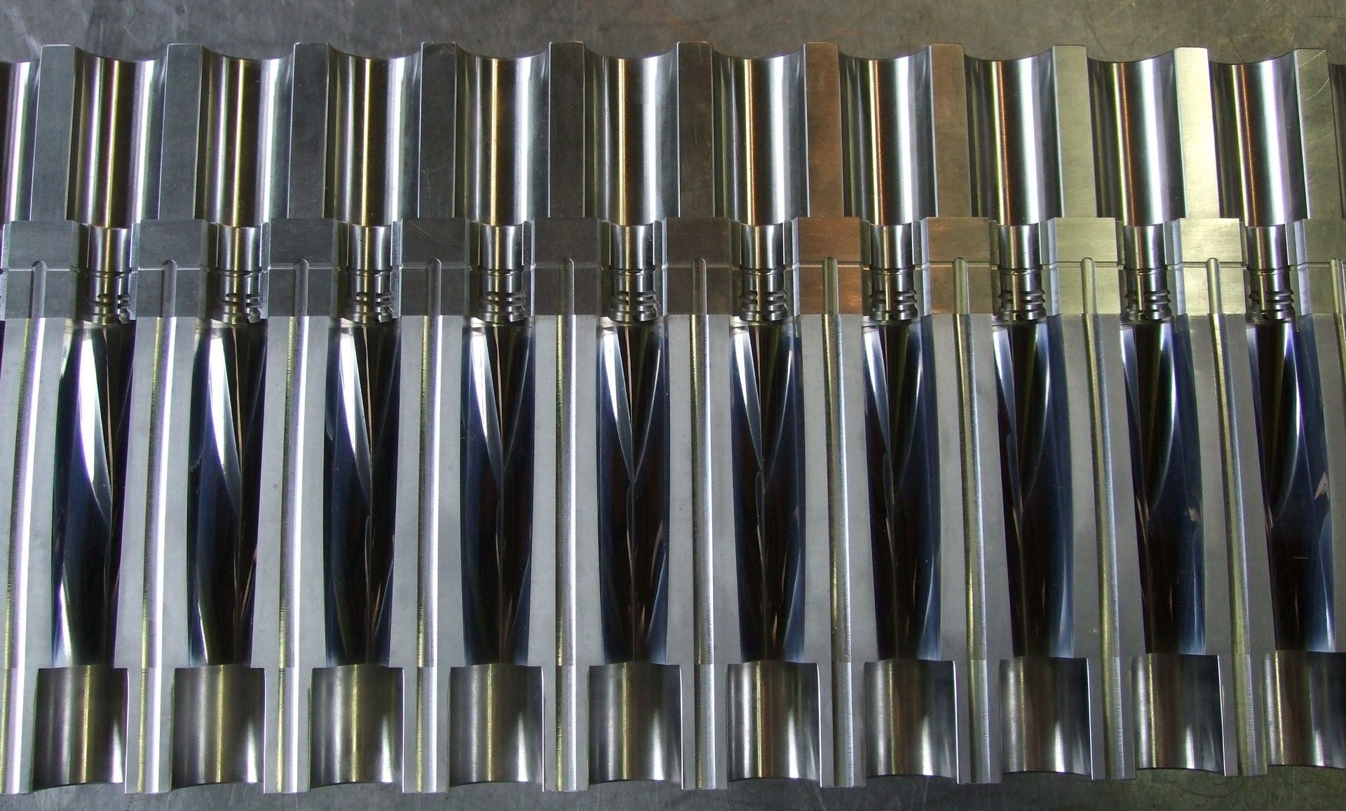 Des rangées d'objets cylindriques chromés brillants, coiffés d'or, soigneusement alignés côte à côte.