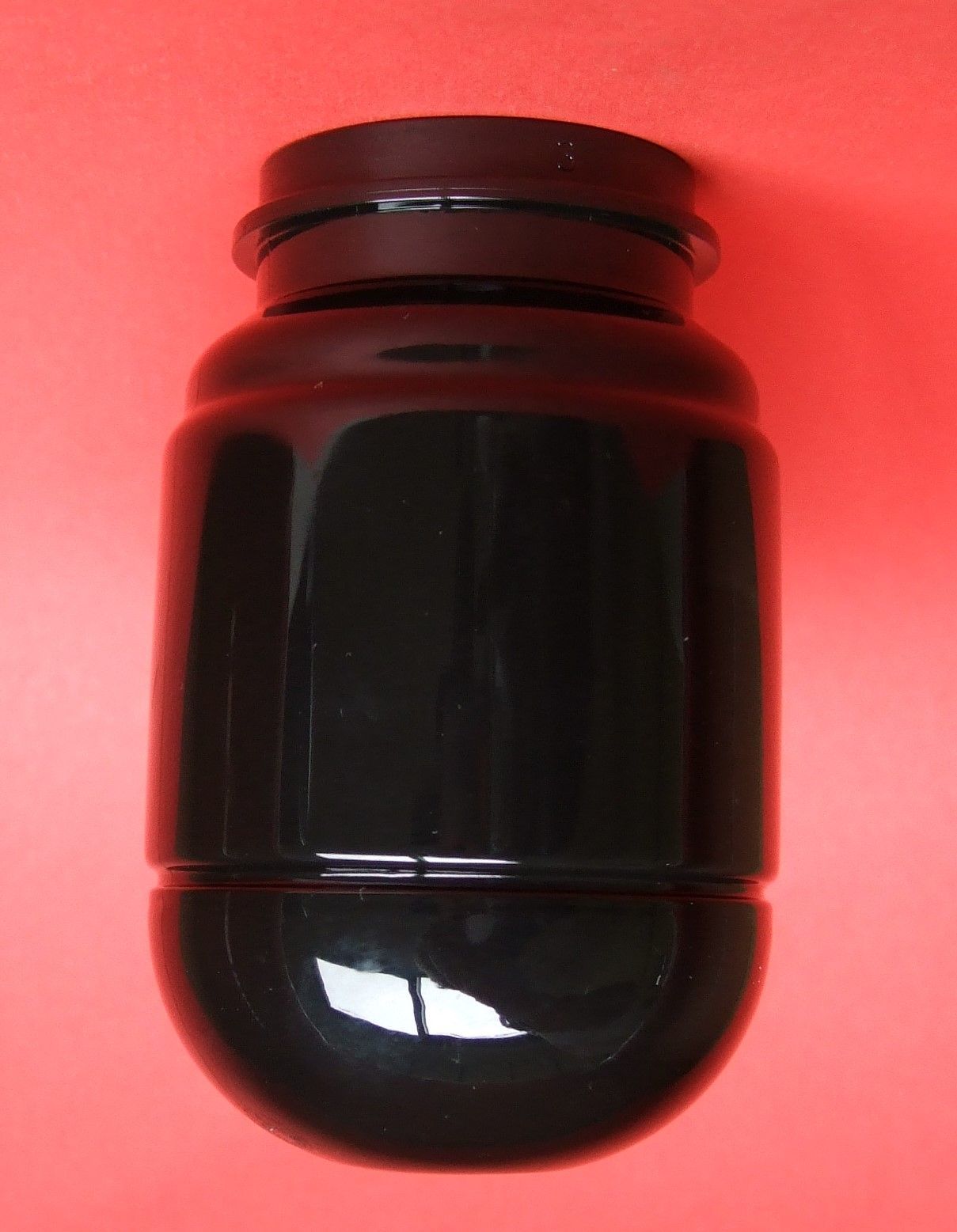 Pot ambré foncé avec couvercle noir sur fond rouge