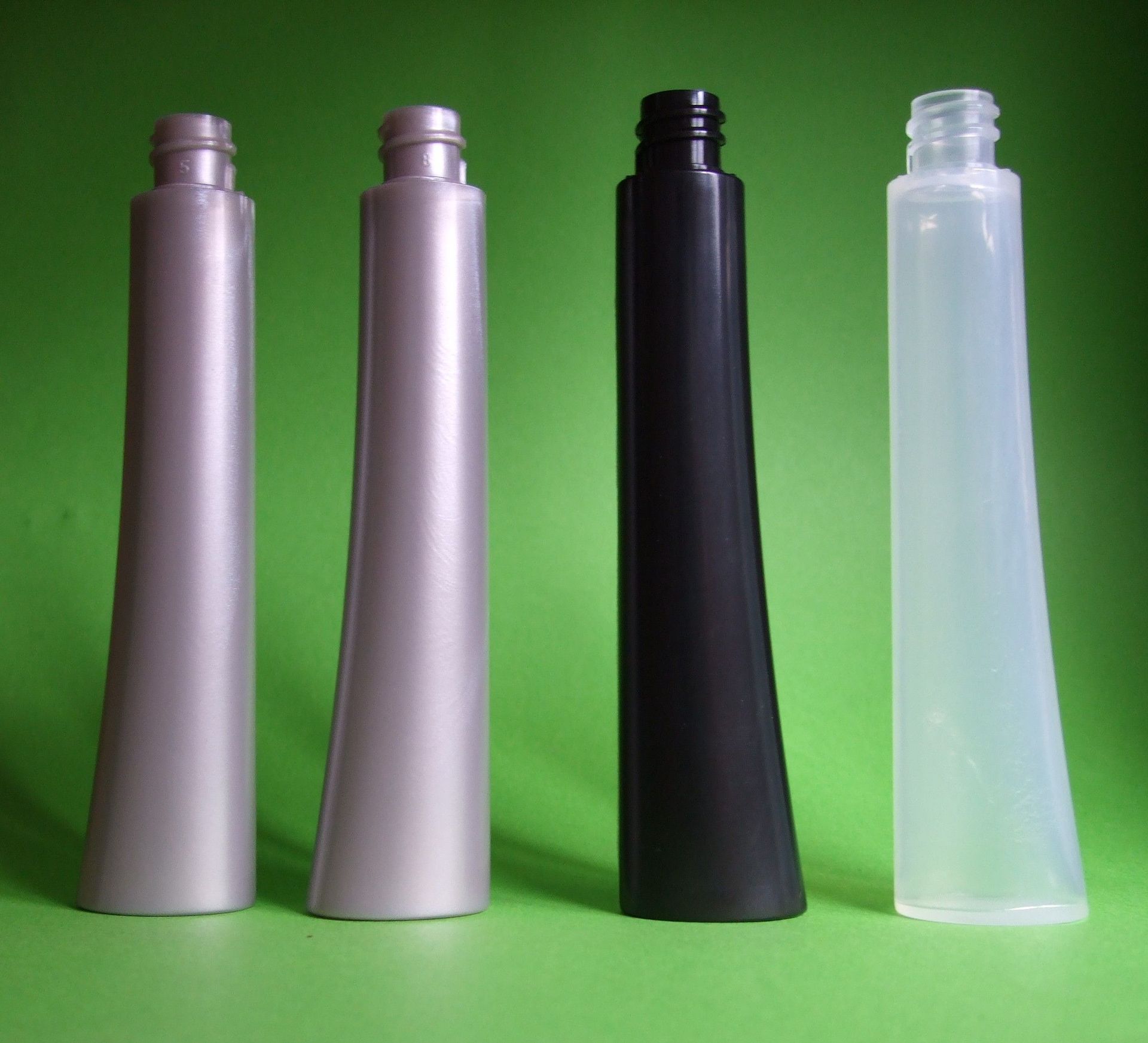 Quatre bouteilles réutilisables en plastique argenté, noir et translucide sur fond vert