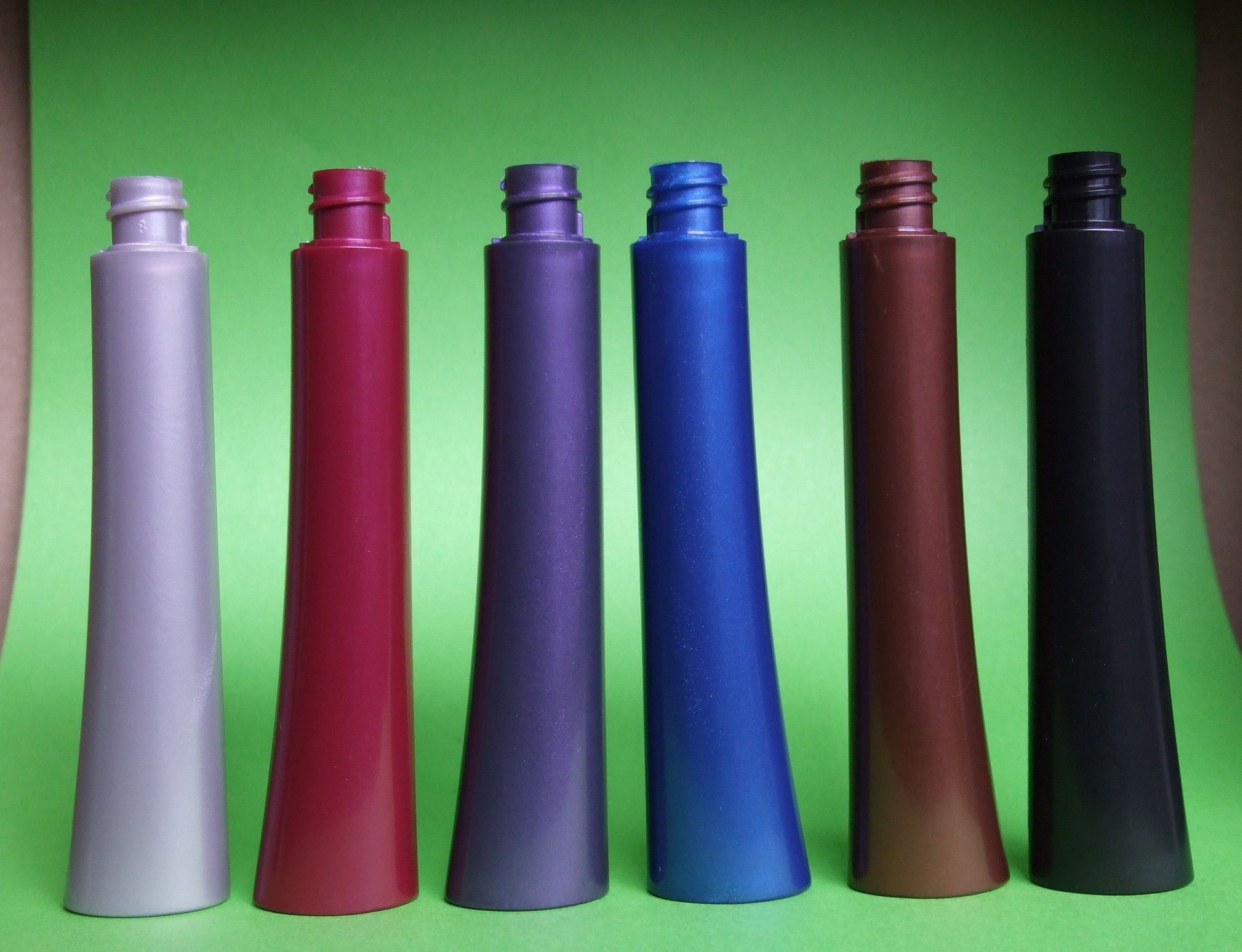 Six bouteilles colorées alignées sur un fond vert vif