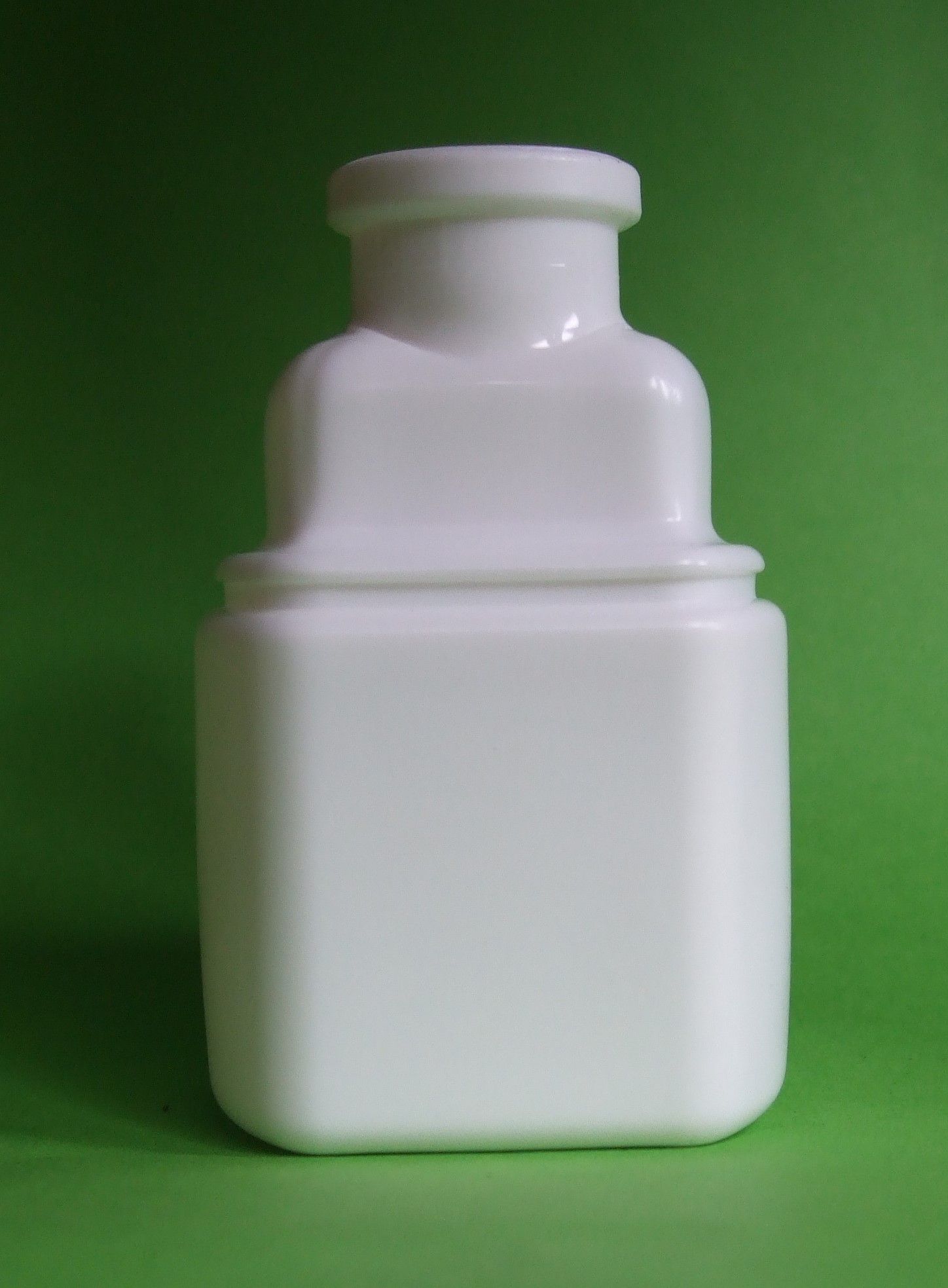 Bouteille en plastique blanc avec un bouchon arrondi sur fond vert