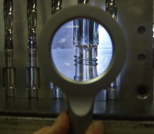 Loupe utilisée pour observer un cylindre métallique dans un environnement de laboratoire ou industriel