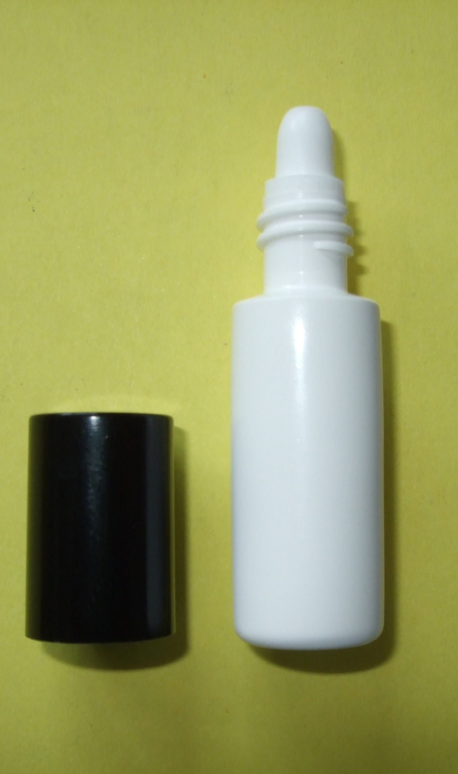 Flacon vaporisateur blanc avec bouchon noir sur fond jaune