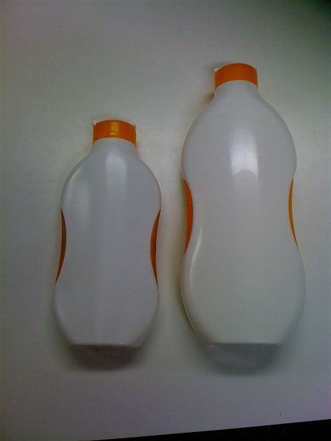 Deux bouteilles de détergent blanches à bouchon orange posées sur une surface plane, une petite et une grande.