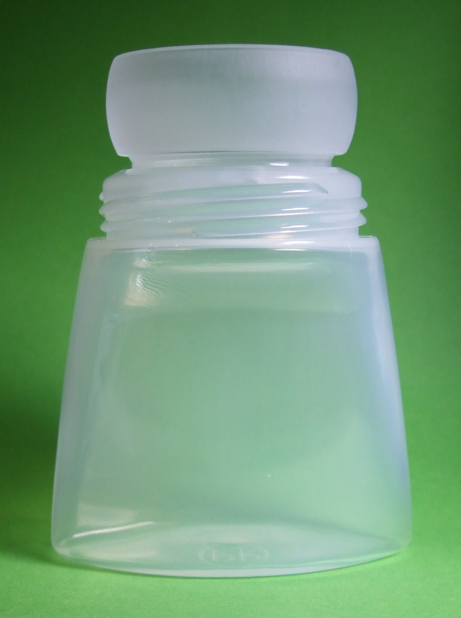 Petite bouteille en plastique translucide avec un bouchon blanc sur fond vert