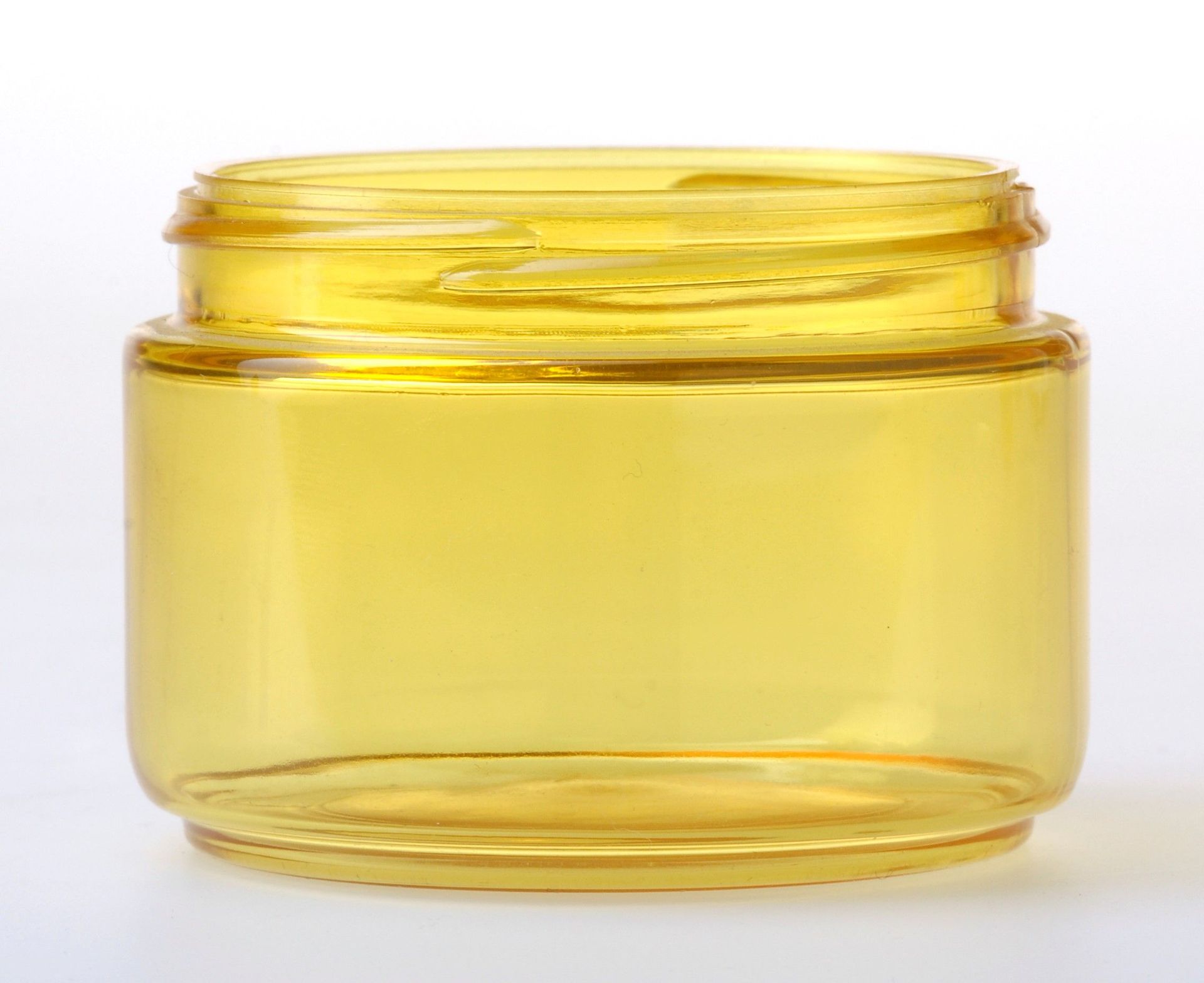 Petit pot transparent rempli de crème ou de gel jaune sur fond blanc