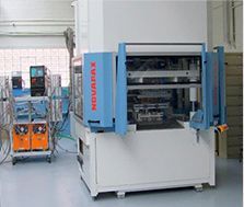 Grosse machine industrielle bleue dans une usine, avec des équipements et des câbles à proximité