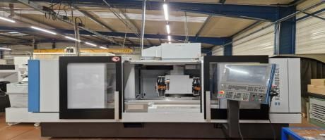 Grande machine CNC industrielle dans un atelier, avec centre ouvert et panneau de commande sur la droite.