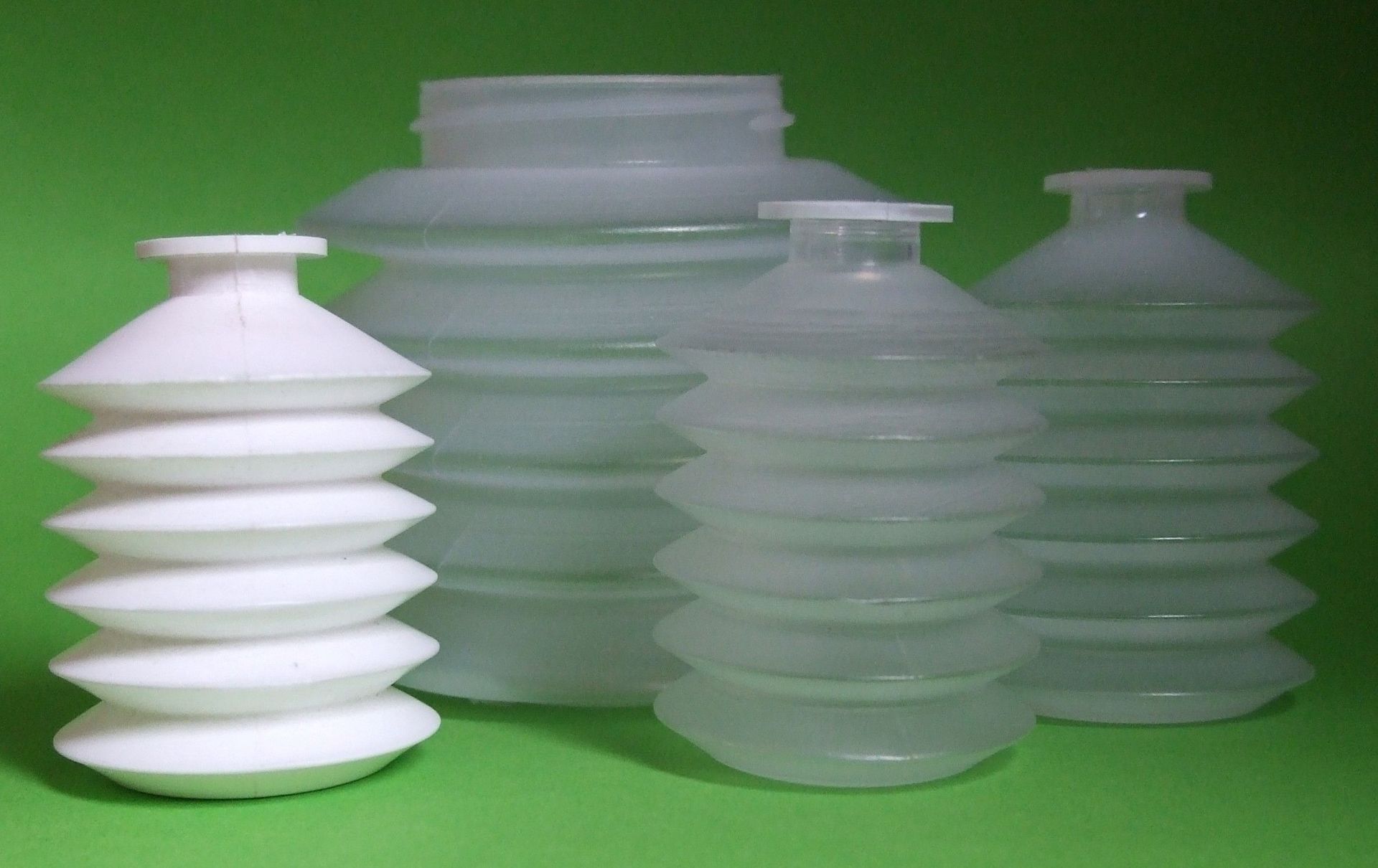 Quatre récipients en plastique translucide et un récipient blanc empilé sur une surface verte.