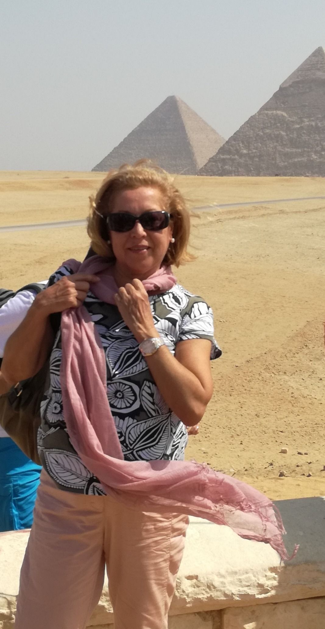 Mujer con gafas de sol y bufanda frente a las pirámides.