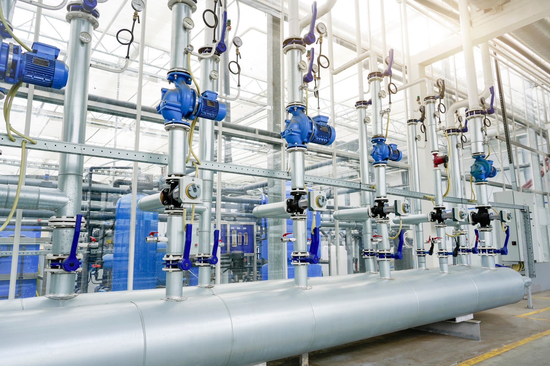 Tuyaux et vannes industriels dans une usine. Tuyaux argentés avec des vannes bleues.