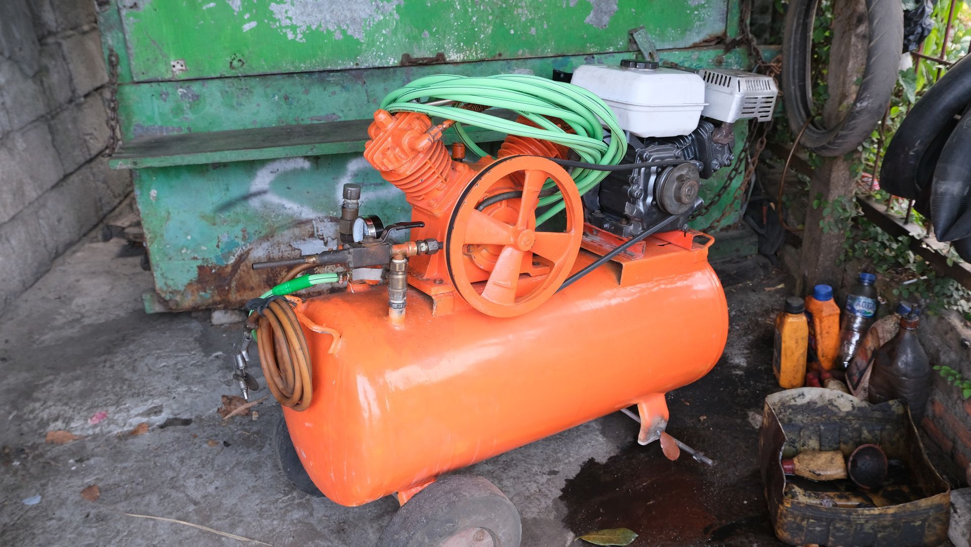 Compresseur d'air orange avec un tuyau vert.